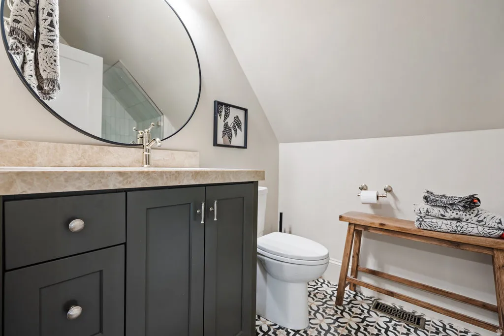 ADU Bathroom featuring a dark gray vanity with a light-colored countertop, an oval mirror, and patterned floor tiling