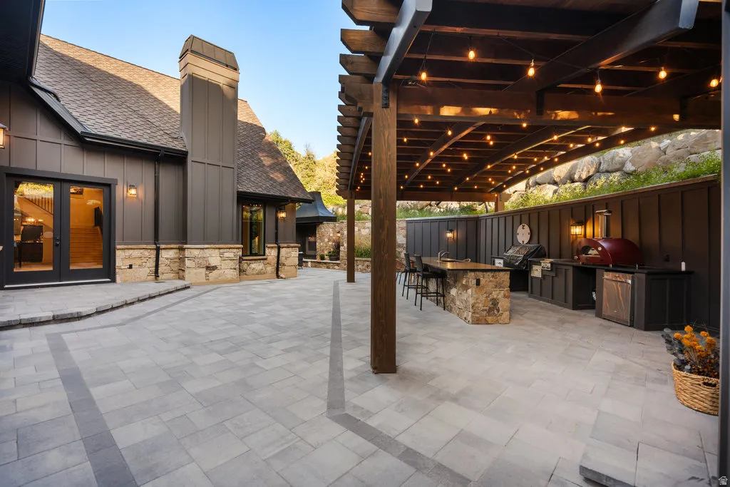 Expansive paver patio with an integrated outdoor kitchen featuring built-in appliances and a stone-clad island
