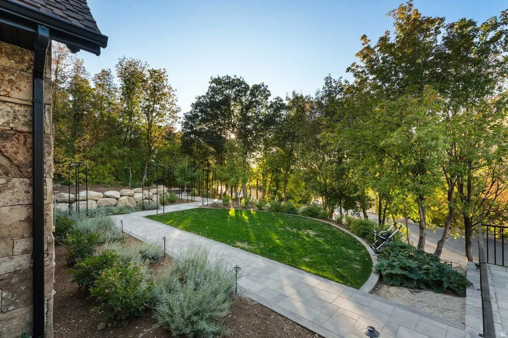 Manicured lawn area featuring a curved stone border, surrounded by mature trees