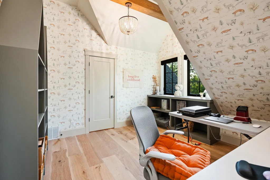 Room featuring sloped ceilings, light wood-finish flooring, and a modern chandelier