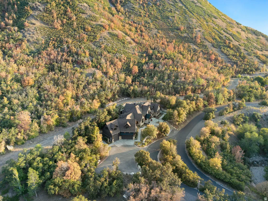 Custom residence nestled within a mountainous setting, featuring a multi-gabled roofline and a paved driveway