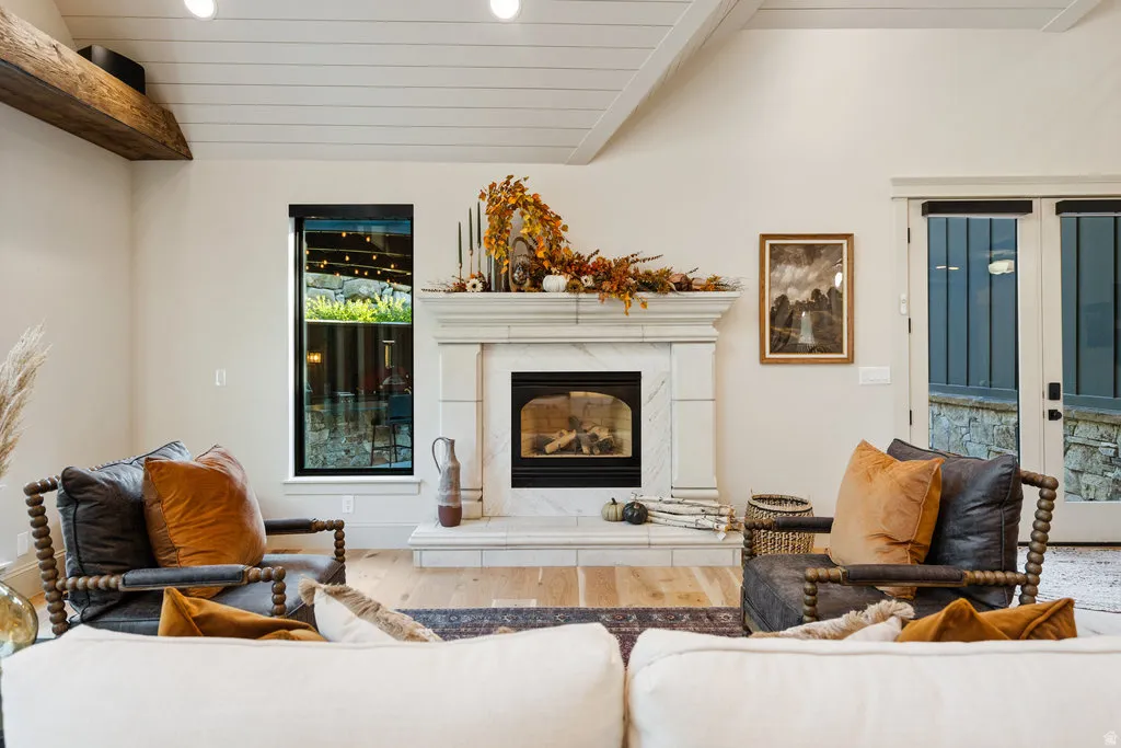 Living area featuring a prominent fireplace with a marble-finish surround and hearth, flanked by a tall vertical window with black trim and double doors