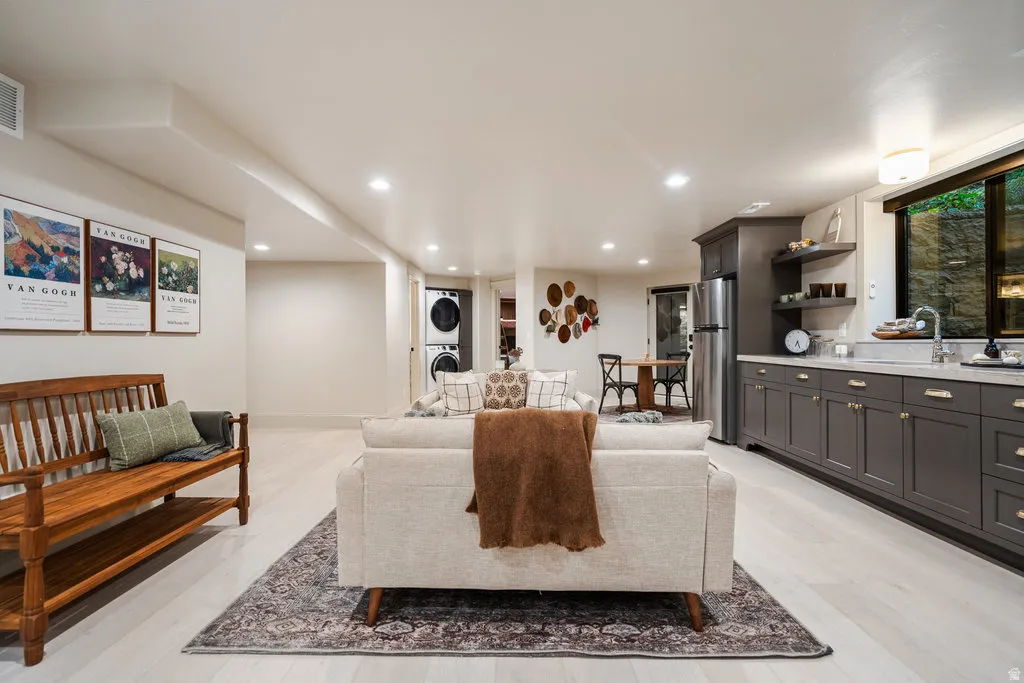 BASEMENT Expansive lower level featuring light wood-finish flooring, recessed lighting, and a full kitchen with dark cabinetry, stainless steel appliances, and a window