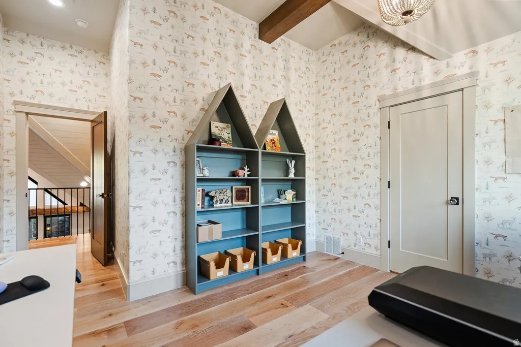 Room featuring patterned wall covering, wood-finish flooring, a built-in house-shaped shelving unit, and a solid interior door