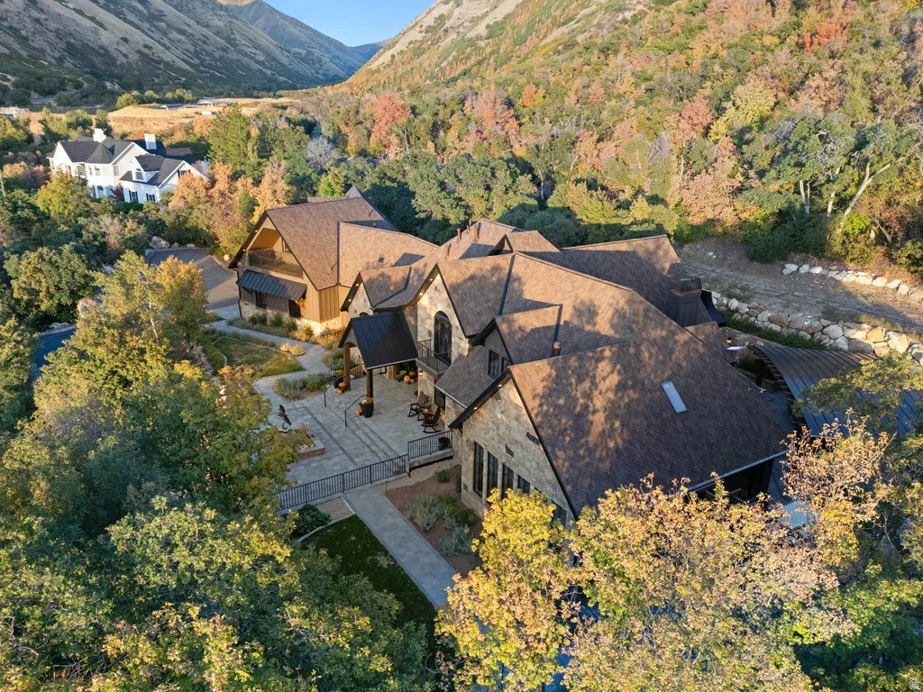 Expansive property featuring a stone and wood exterior, multiple gables, a paved patio, and a covered entrance