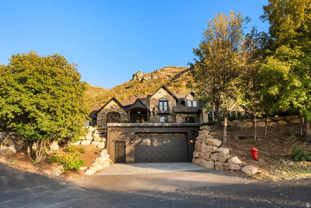 Stone and stucco exterior residence featuring an oversized multi-car garage and a stone retaining wall