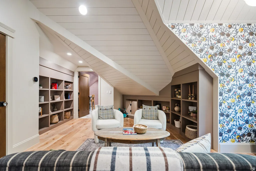 Accent wall with botanical pattern wallpaper, wood-finish flooring, built-in shelving, paneled ceiling, and recessed lighting