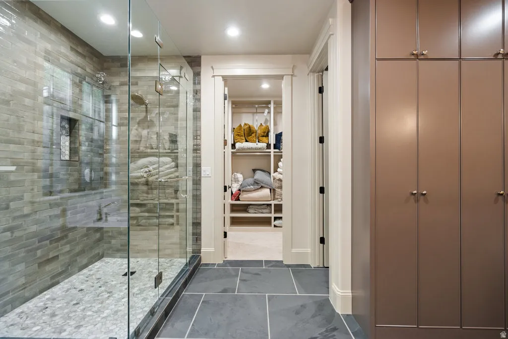 Glass-enclosed shower featuring a tiled bench and a pebbled floor