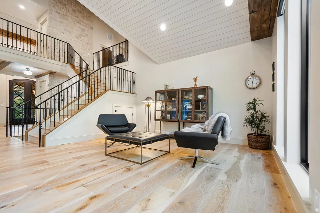 Grand room/family room/living room... a light wood-finish flooring, a two-story staircase with dark wrought iron railings, and a prominent stone accent wall