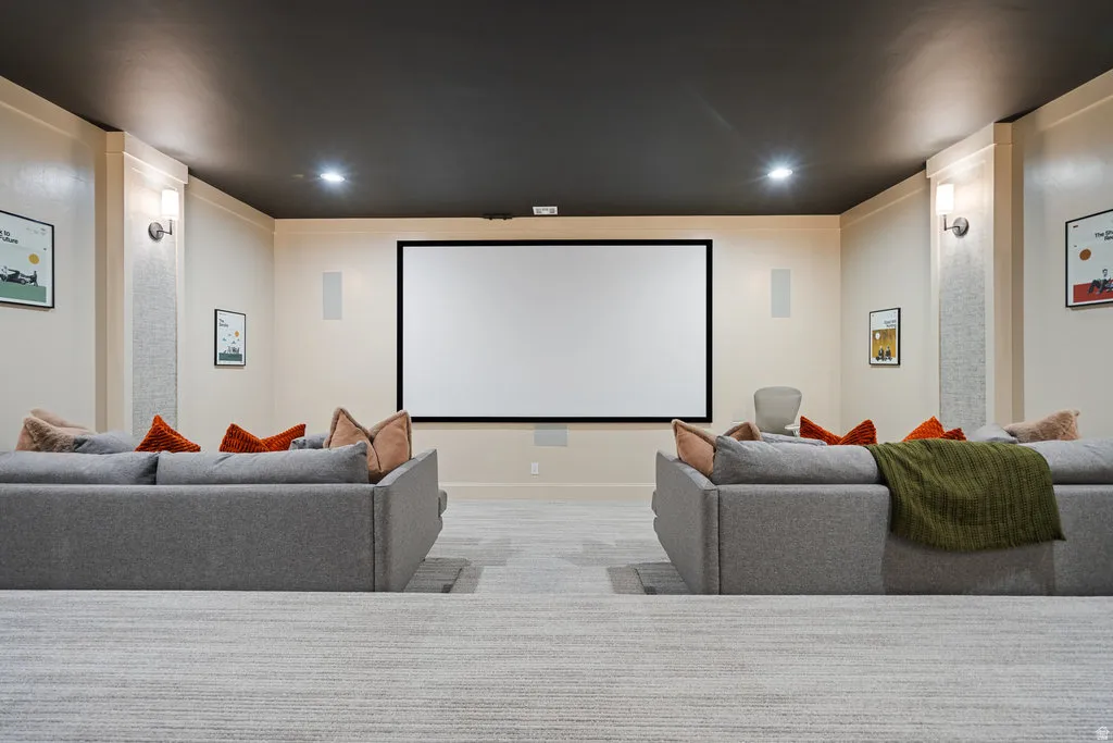 Dedicated media room featuring a large projection screen, integrated wall speakers, and recessed lighting