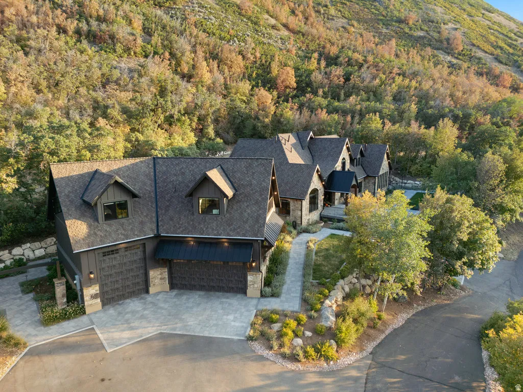 Multi-gabled residence featuring stone and vertical siding, a paved driveway, and multiple garage doors