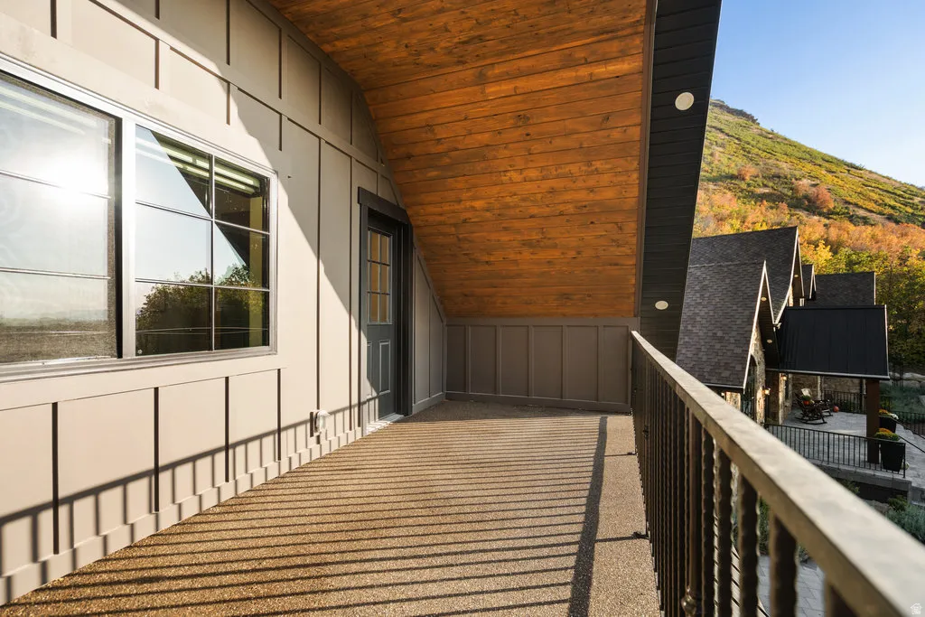 ADU Exterior balcony featuring a textured surface, dark metal railing, and a natural wood-finish ceiling