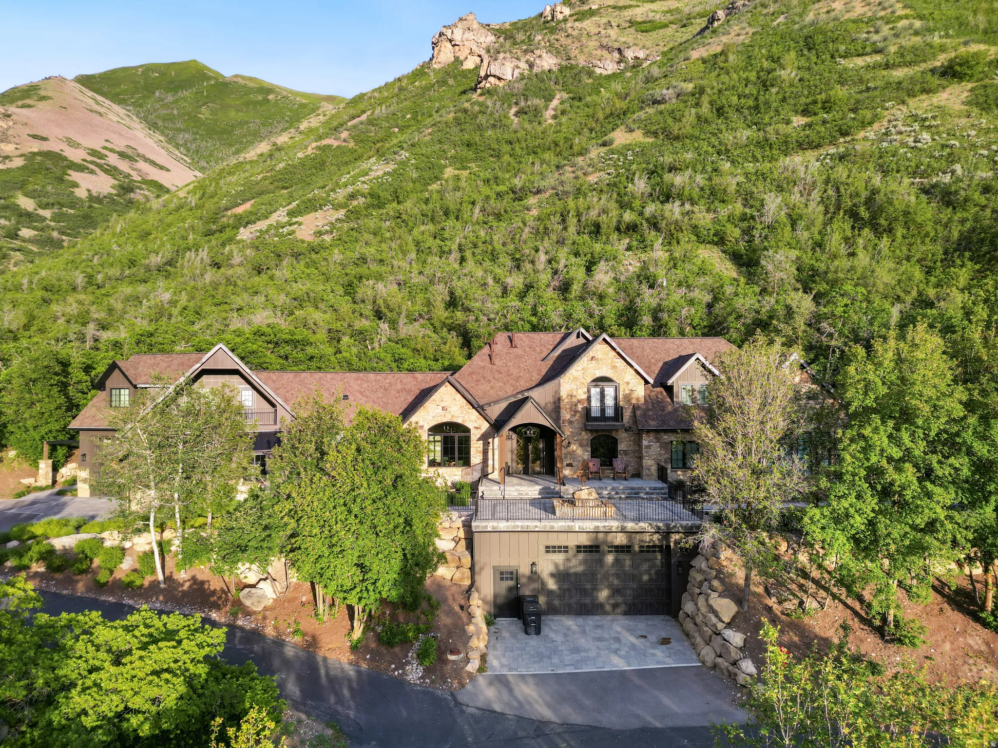 Stone and wood-sided residence featuring a multi-level design and a prominent three-car garage