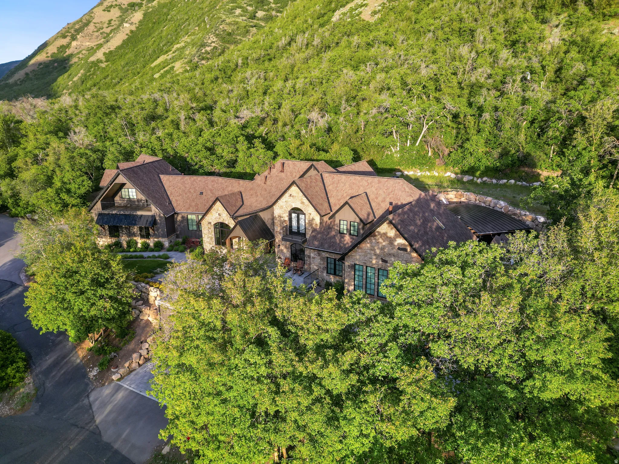 Stone and stucco residence featuring a multi-gabled roofline and dark framed windows