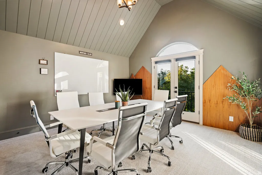 Room featuring a vaulted ceiling with horizontal paneling, light gray painted walls, and light-colored carpeting
