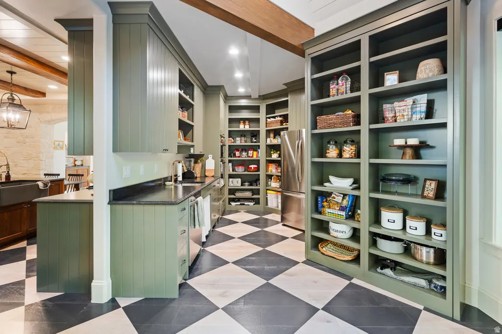 Kitchen featuring custom cabinetry, stainless steel appliances, a black and white checkered floor, stone countertops, and built-in shelving