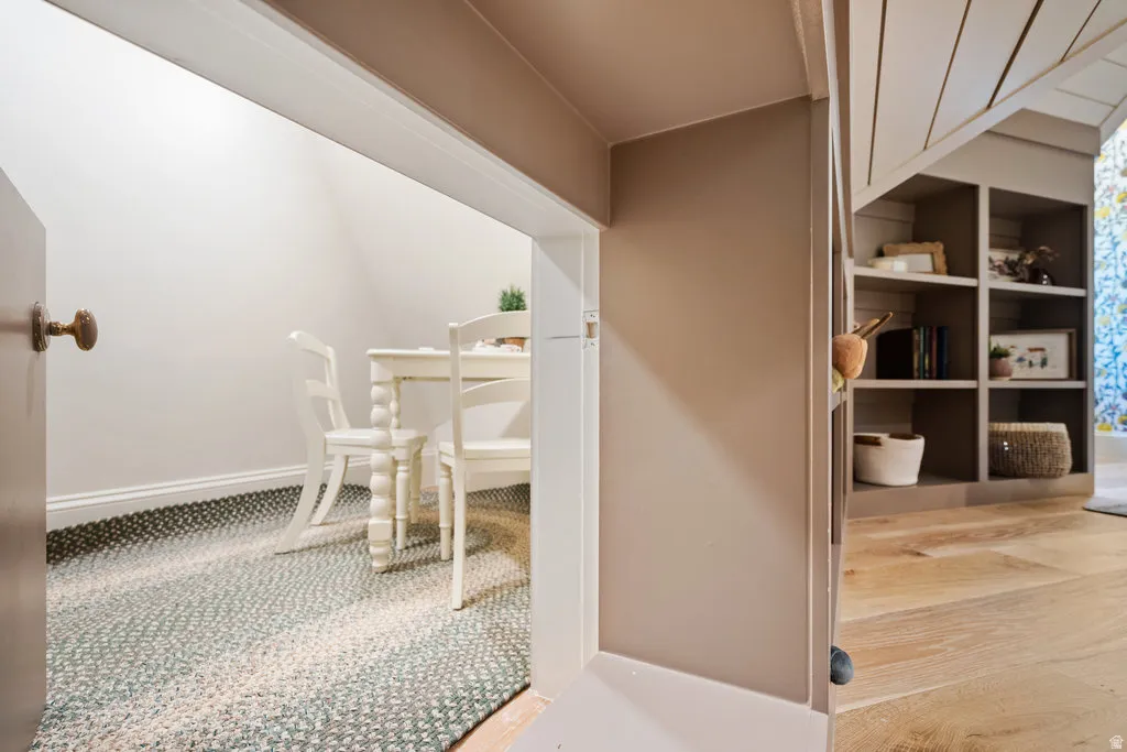Recessed nook with white walls and a braided floor covering, complemented by built-in shelving and light wood-finish flooring