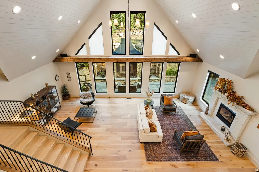 Vaulted ceiling great room featuring light wood-finish flooring, a white paneled ceiling with recessed lighting, an exposed wood beam, and a fireplace with a decorative mantel