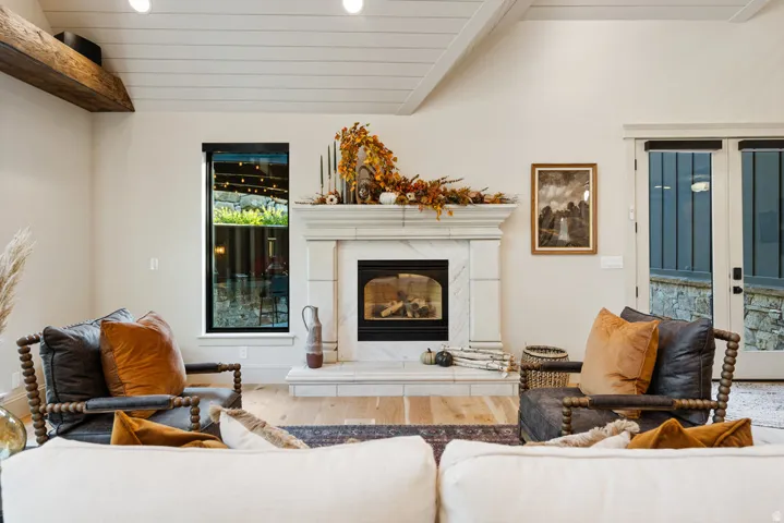 Living area featuring a prominent fireplace with a marble-finish surround and hearth, flanked by a tall vertical window with black trim and double doors