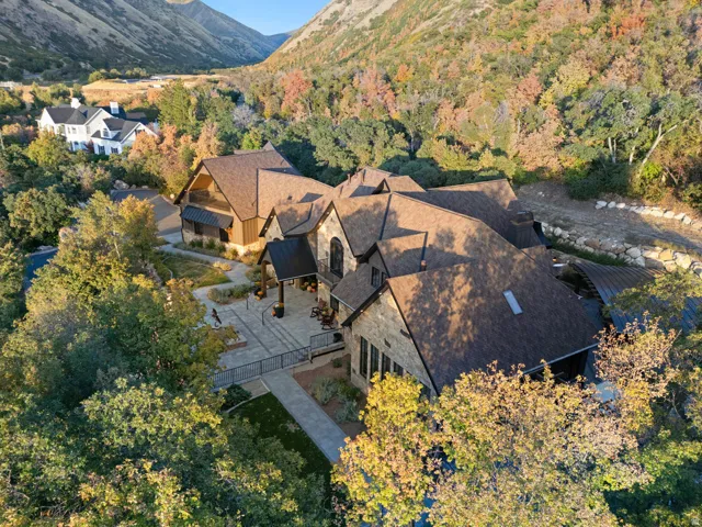 Expansive property featuring a stone and wood exterior, multiple gables, a paved patio, and a covered entrance
