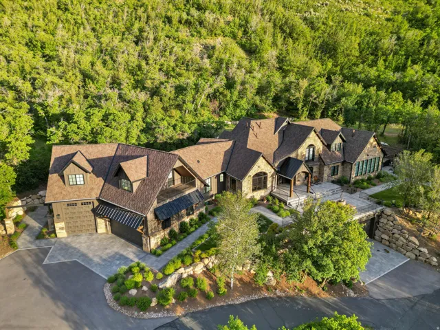 Expansive multi-level residence featuring a stone and wood facade, multiple gabled roofs, and an attached two-car garage