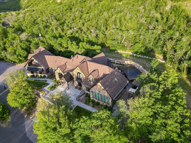 Expansive multi-level stone residence featuring multiple gabled rooflines, dark-framed windows, and an integrated pergola
