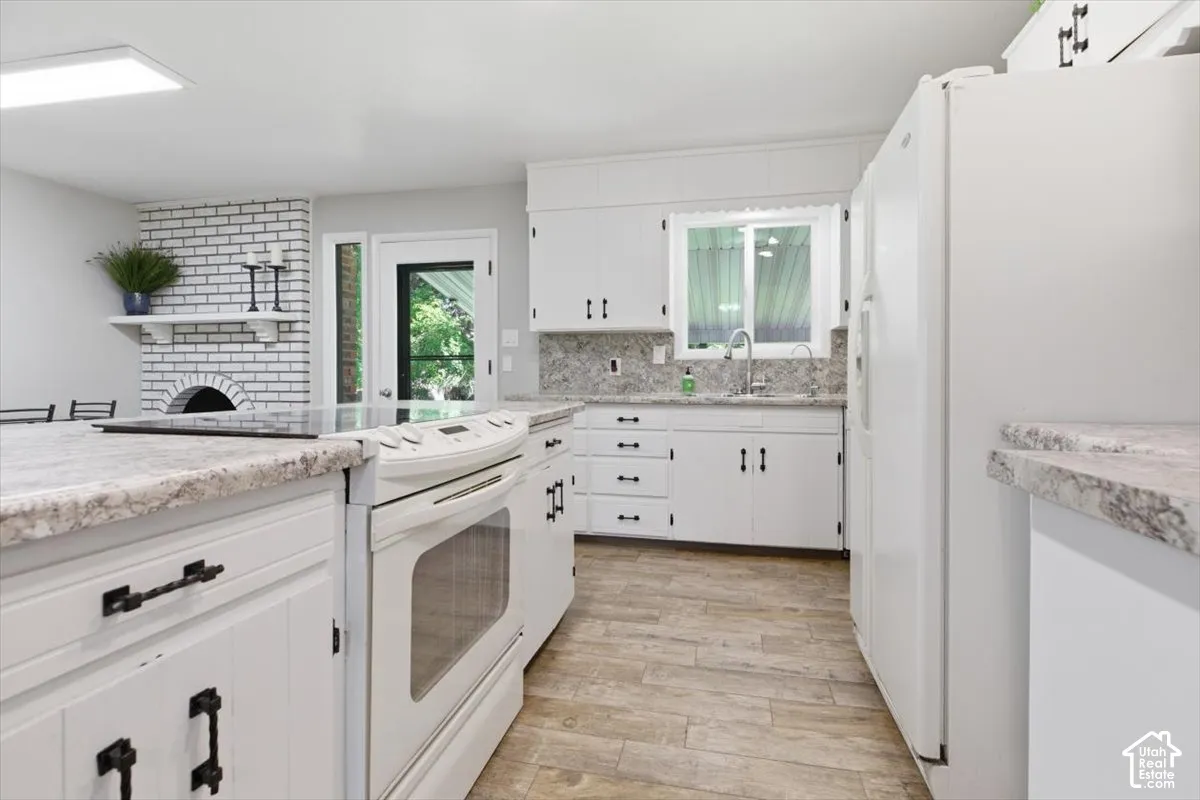 Kitchen featuring white cabinetry with dark hardware, stone-finish countertops, and a full suite of white appliances