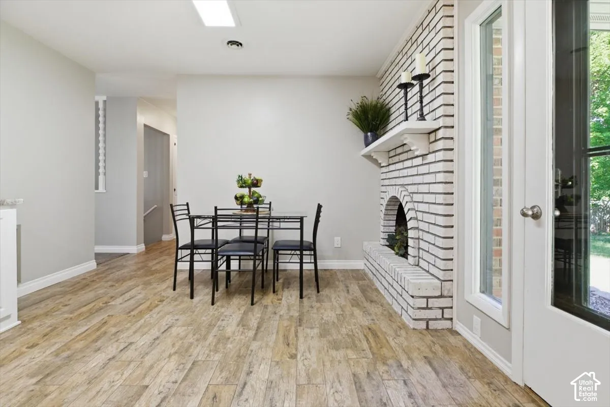 Light-toned wood-finish flooring complements a white-painted brick fireplace with a mantle