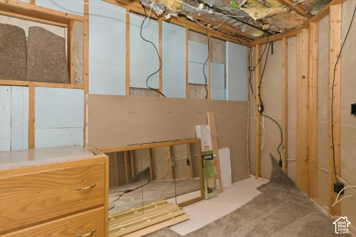Unfinished lower level offering framed walls, visible insulation, and carpet flooring
