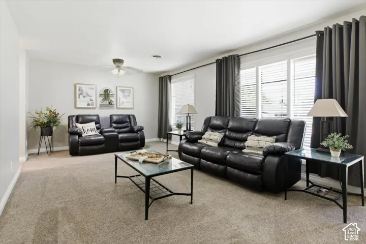 Carpeted living area featuring white walls and multiple windows with blinds and dark gray drapes