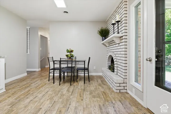 Light-toned wood-finish flooring complements a white-painted brick fireplace with a mantle