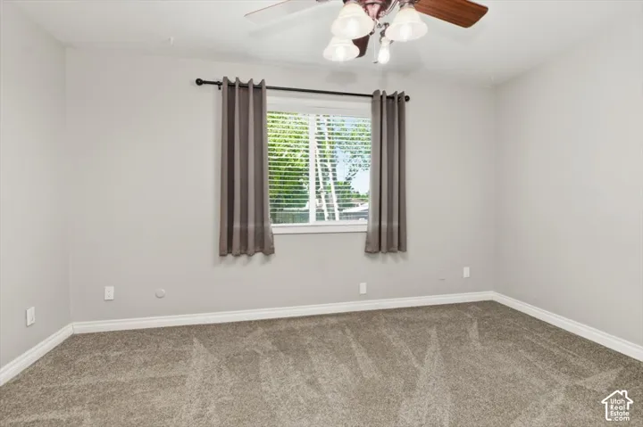Spacious interior room featuring light gray wall paint, white trim, and gray speckled carpet