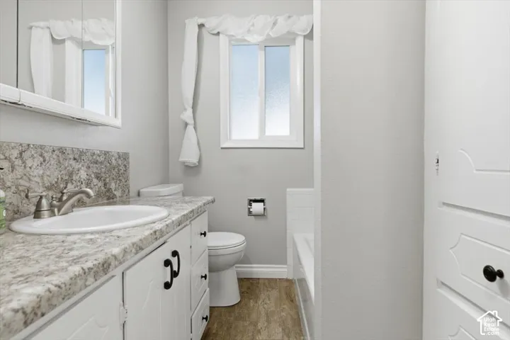 Bathroom vanity featuring a white oval sink with brushed nickel faucet, a speckled countertop, and white cabinetry with black hardware
