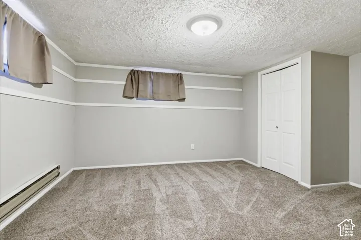 Carpeted room featuring light gray walls, white trim, and a bi-fold closet