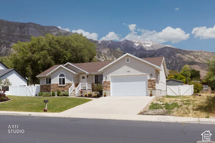Stucco exterior with stone veneer accents, an arched window, a two-car garage, and a concrete driveway