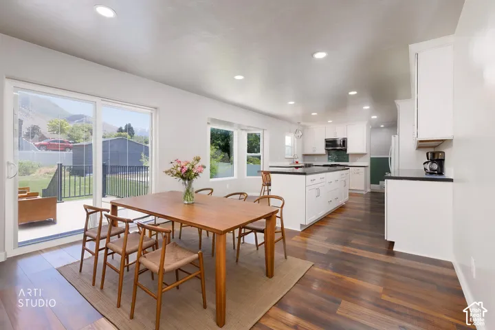 Open-concept dining area featuring wood-finish flooring, recessed lighting, and a sliding glass door to an outdoor patio