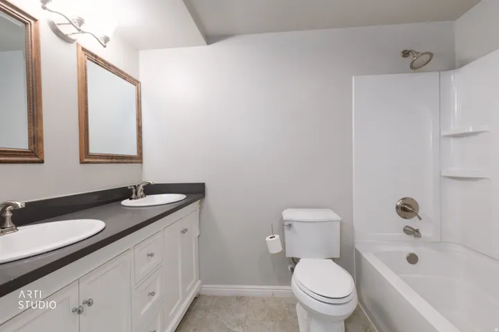 Bathroom featuring a double vanity with white cabinetry and dark countertops