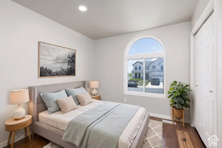 Arched window offering natural light, dark wood-finish flooring, recessed lighting, and white walls