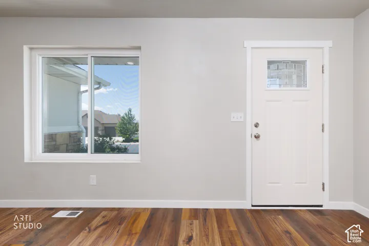 Entryway featuring wood-finish flooring, a white paneled door with decorative glass, and a large sliding window with white trim