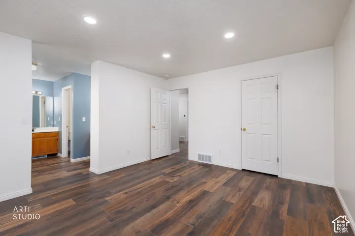 Spacious room featuring wood-finish flooring, recessed lighting, and white baseboards