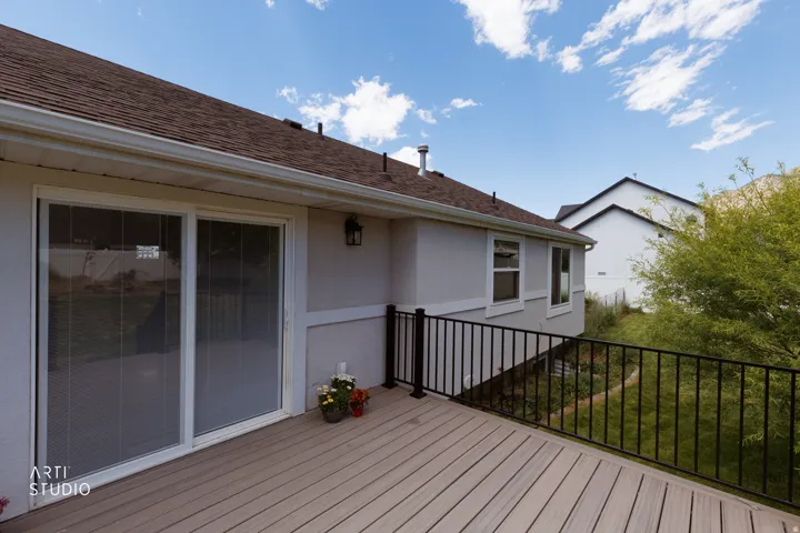Outdoor deck featuring composite decking, black metal railing, and direct access to interior spaces via sliding glass doors