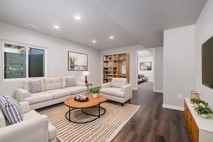 Open living area featuring wood-finish flooring, recessed lighting, and a built-in wooden bookcase