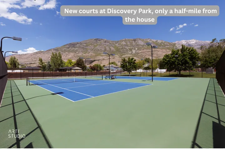 Tennis courts featuring blue and green playing surfaces, surrounded by fencing and tall light poles