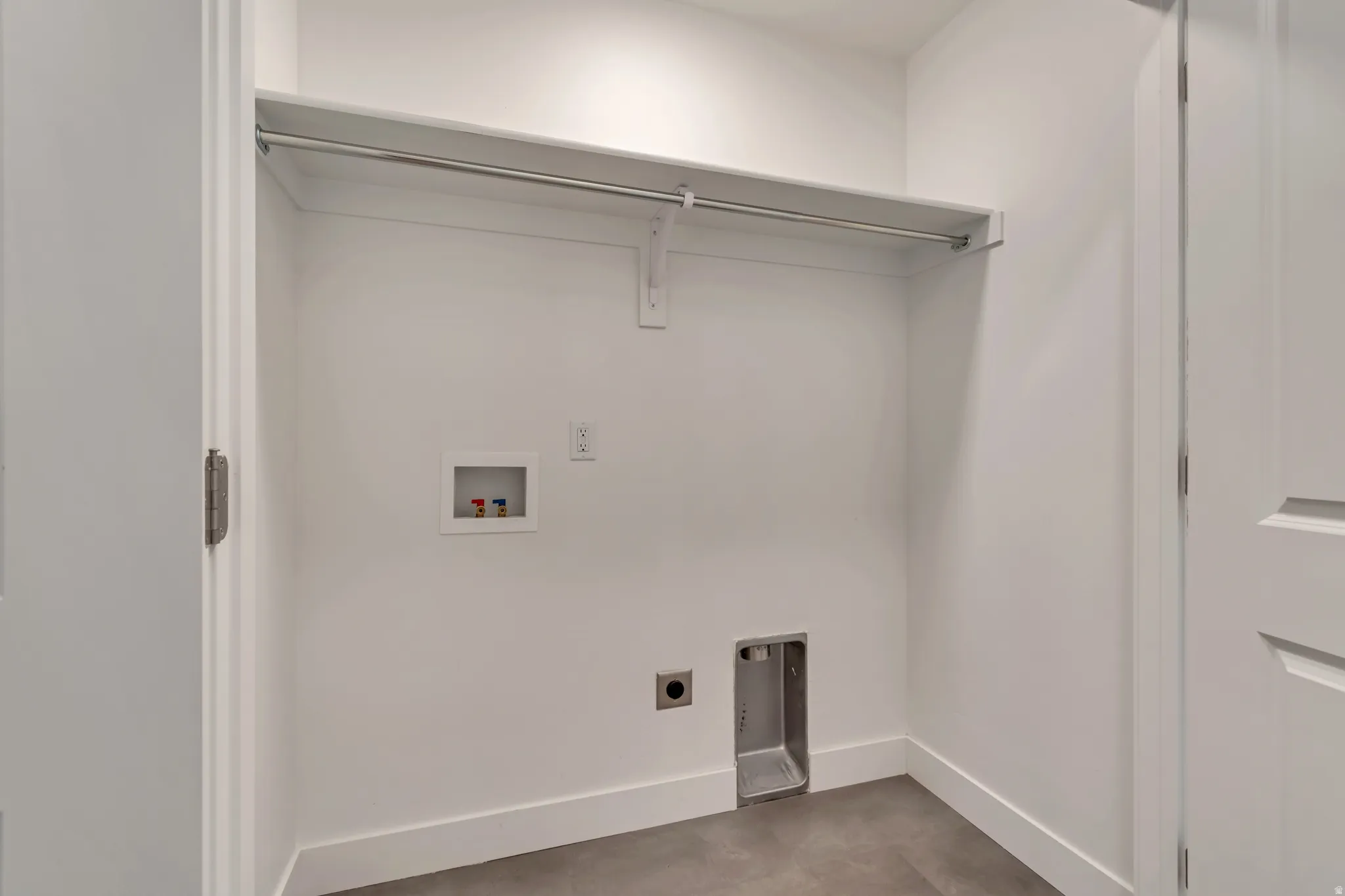 Dedicated laundry area featuring a built-in shelf, hanging rod, and utility hookups
