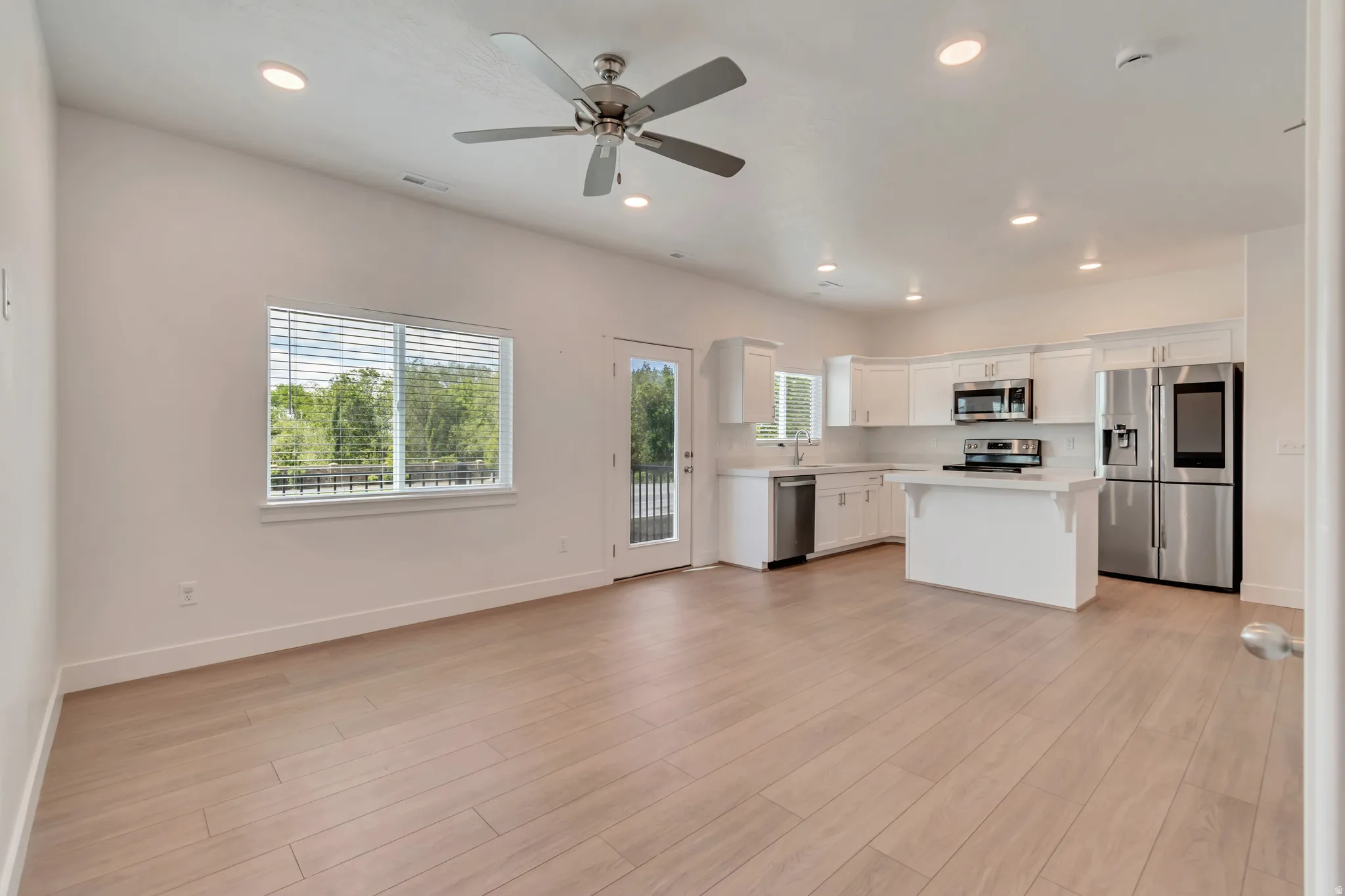Open-concept living space featuring wood-finish flooring, recessed lighting, and a ceiling fan