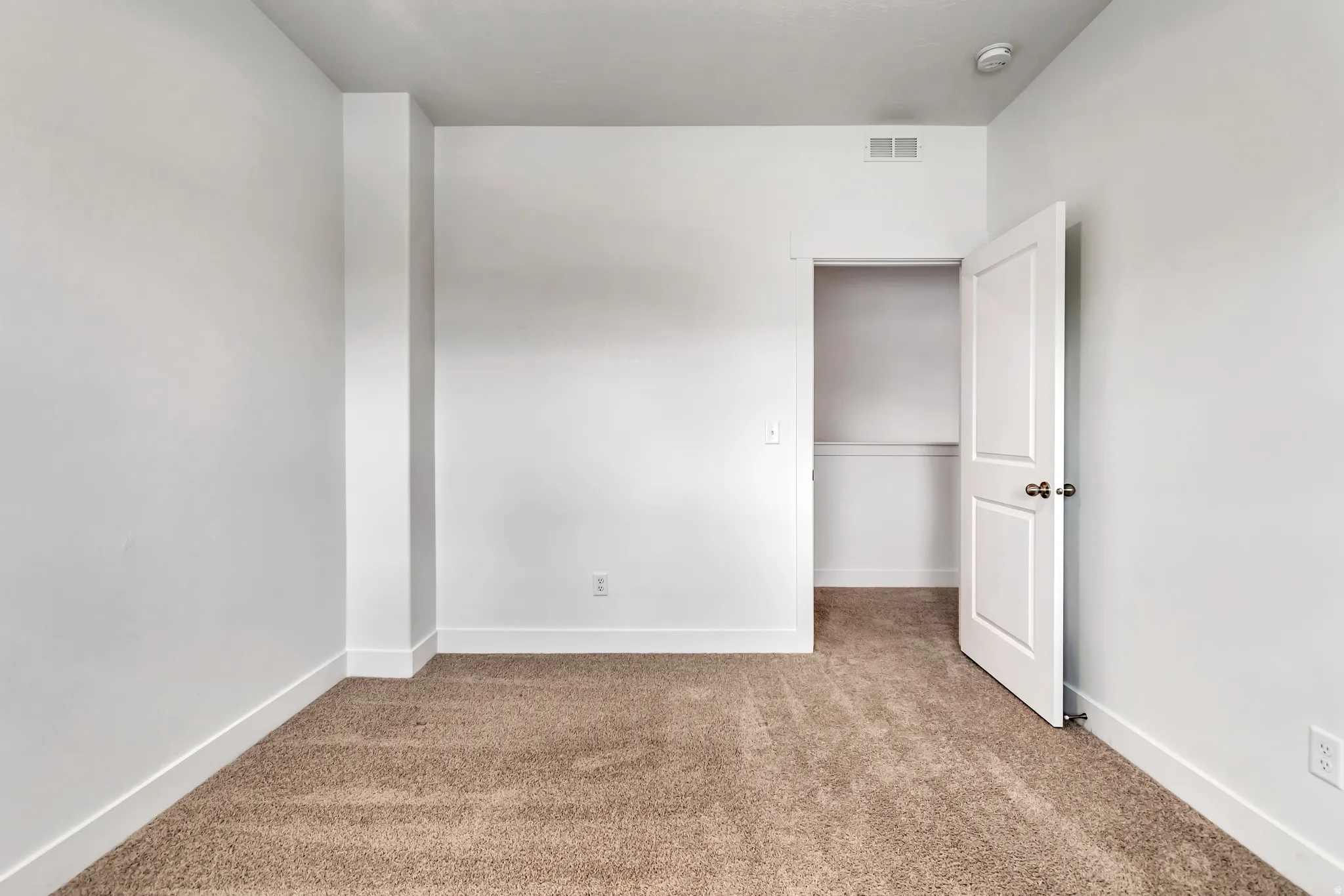 Carpeted interior room featuring white painted walls and trim