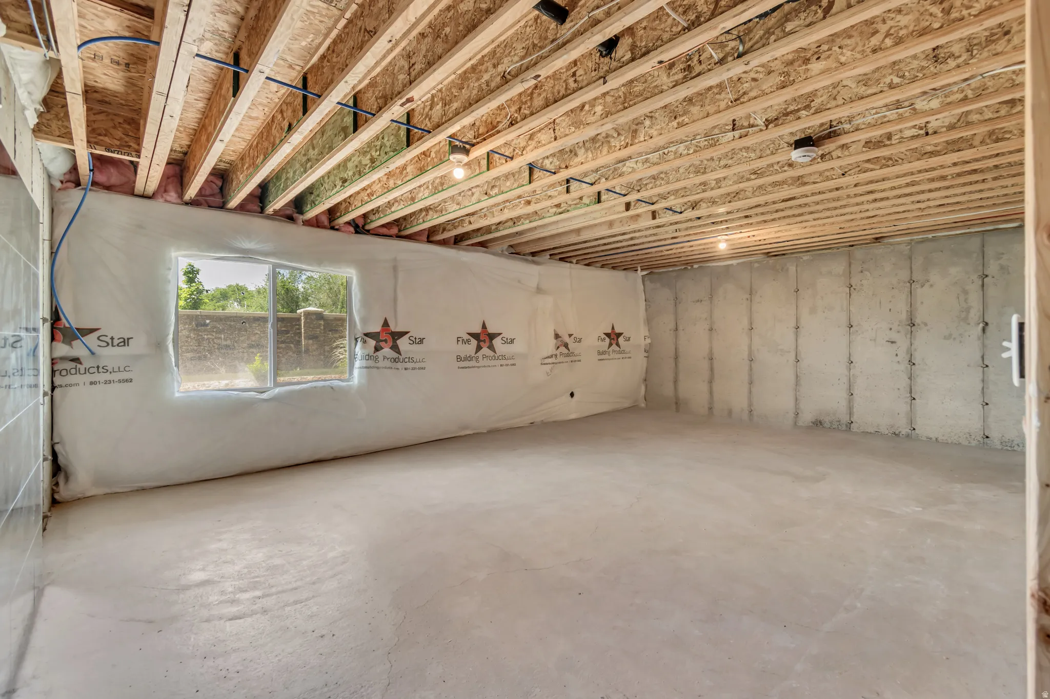 Unfinished basement with exposed ceiling joists and concrete flooring
