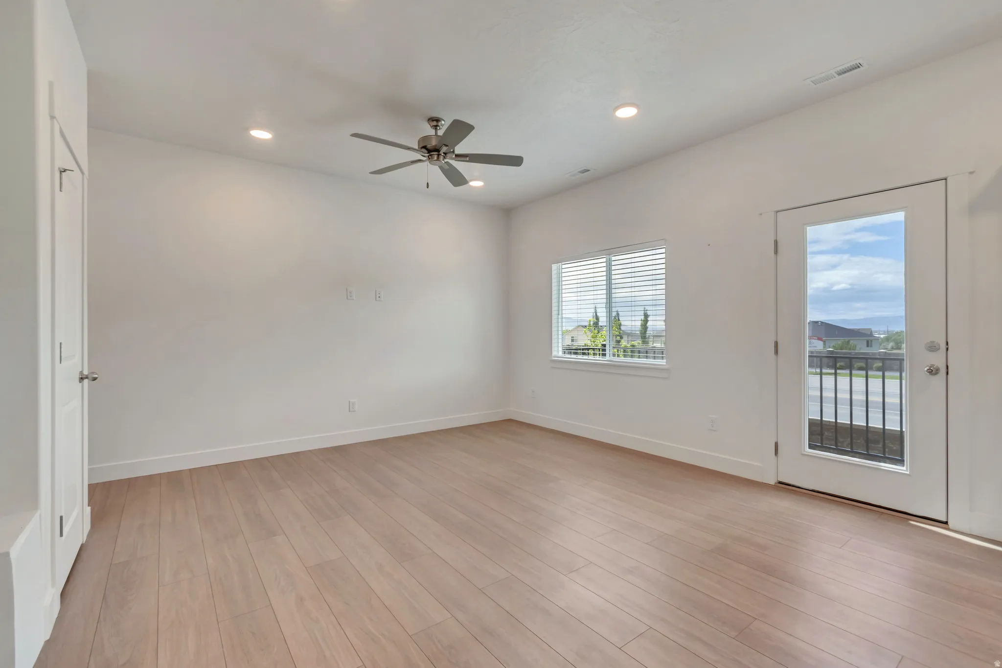 Spacious room featuring light wood-finish flooring, recessed lighting, and a ceiling fan