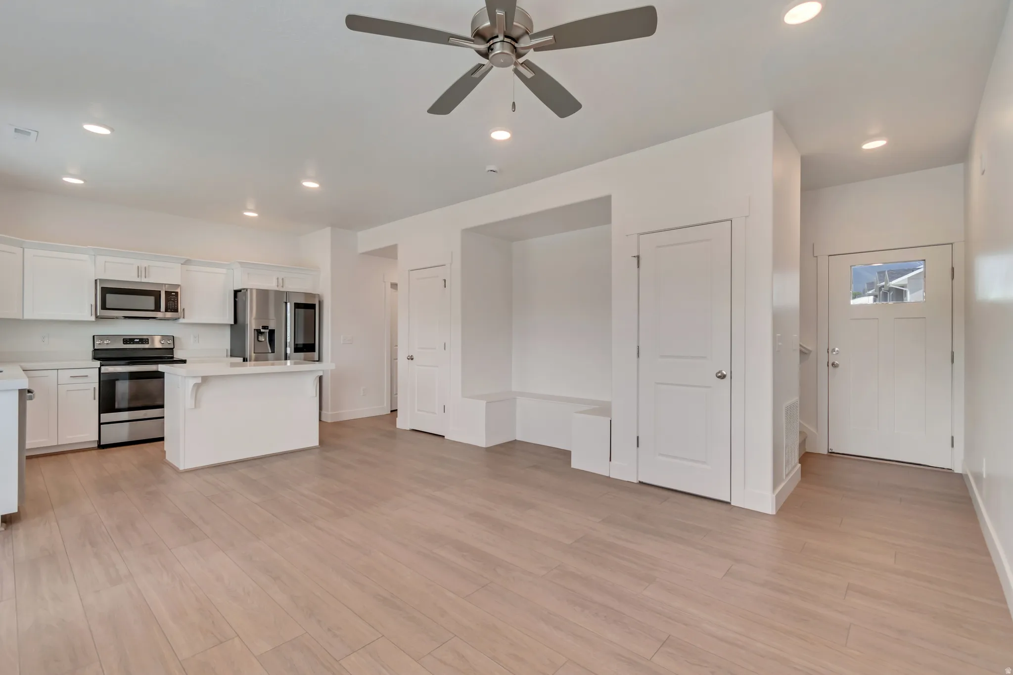 Open-concept living area with wood-finish flooring, recessed lighting, and a ceiling fan