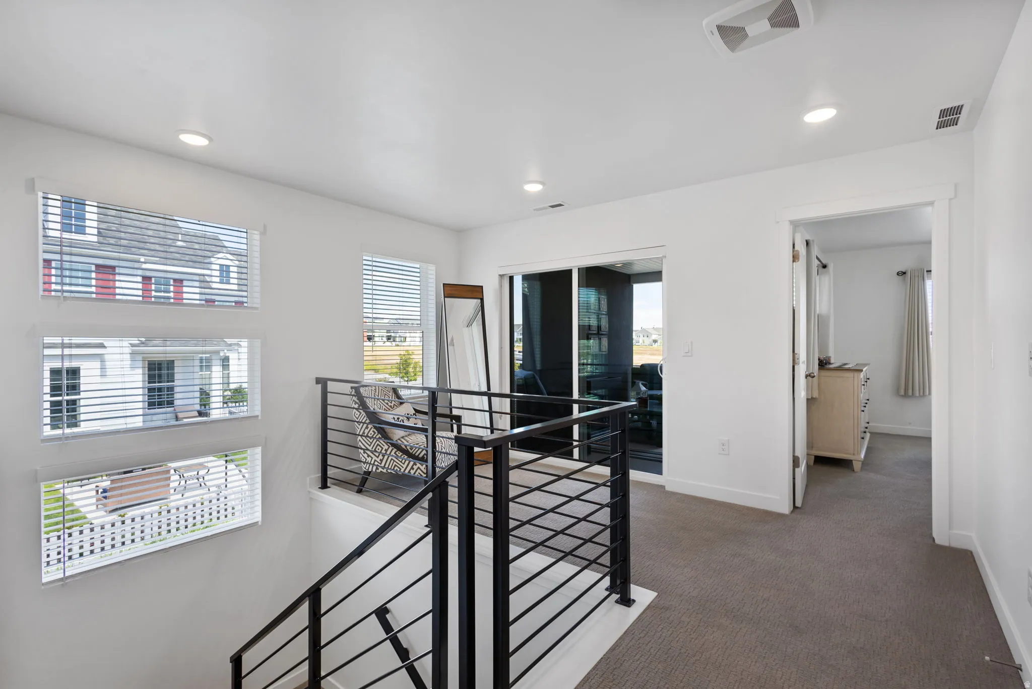 Upper-level landing featuring a contemporary black metal railing system and recessed lighting